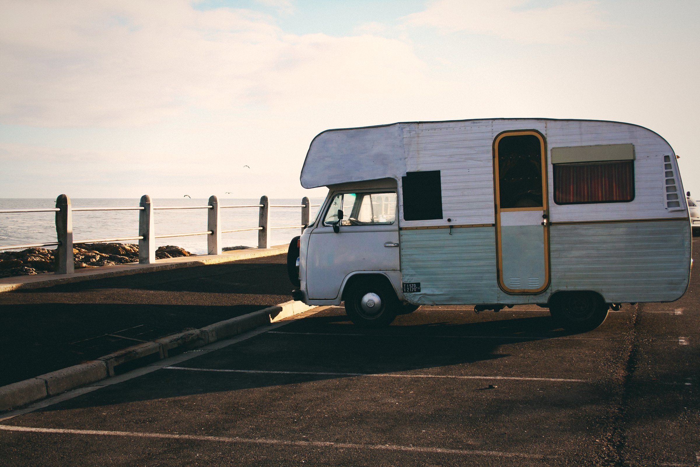 Vintage white caravan parked by the ocean